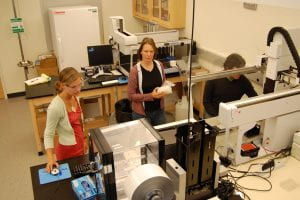 a photo of students and staff working together in the lab on the pinning robot